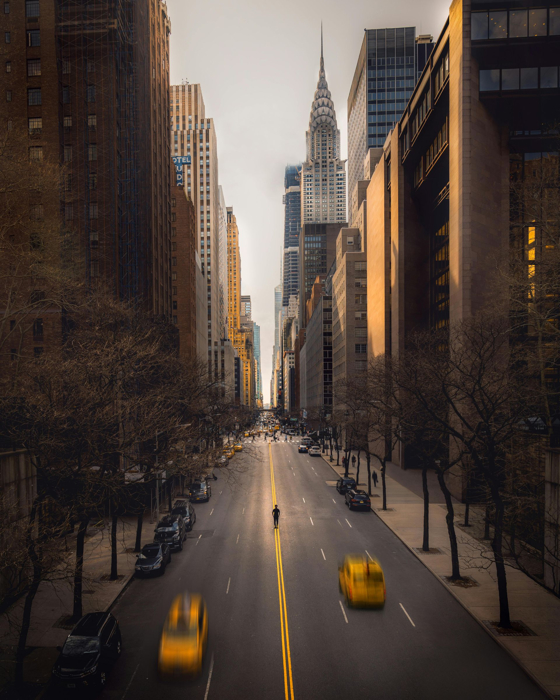 Street scene in New York City with tall buildings, yellow taxis, and bare trees.